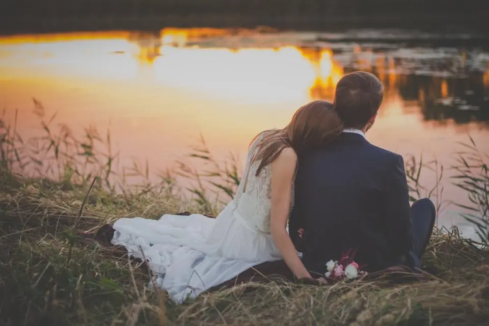 Pareja de novios viendo el atardecer a la orilla de un lago