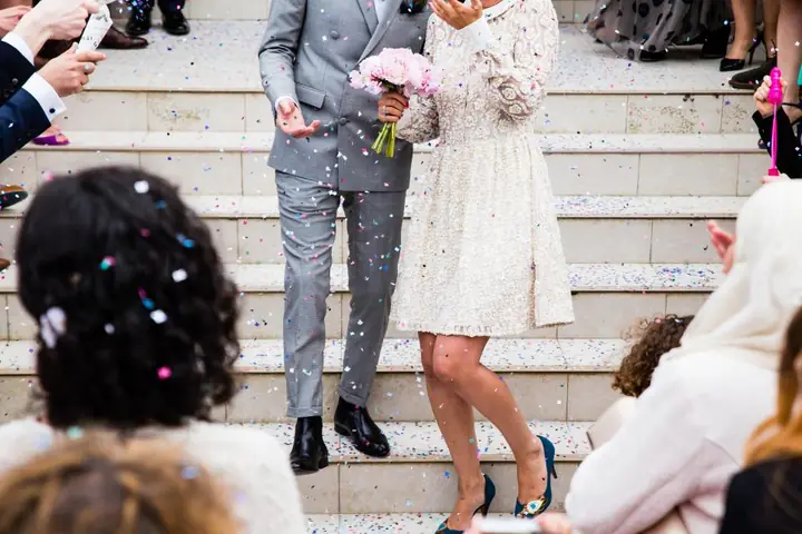 Novios bajando una escalinata entre confeti después de la boda
