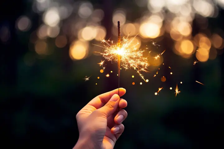 Mano sosteniendo una bengala encendida en una fiesta de noche